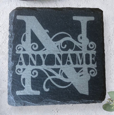A slate coaster engraved by Sweet Pea Laser boutique. It is square and has a large capital letter behind 'any name'. This is to show you can have it engraved to have any name on, and the first letter will be in capital.