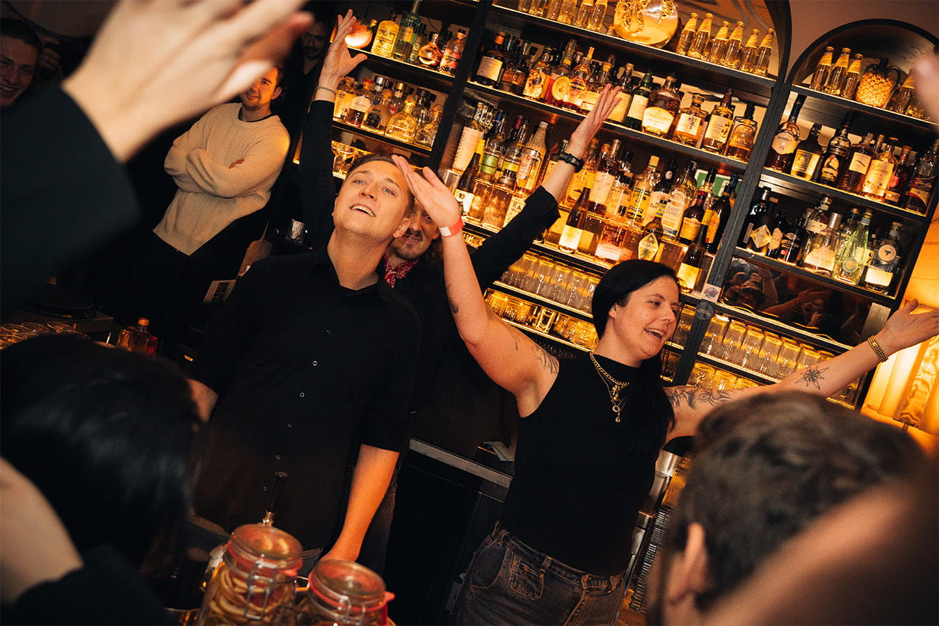 Feiernde, singende Personen hinter dem Bartresen