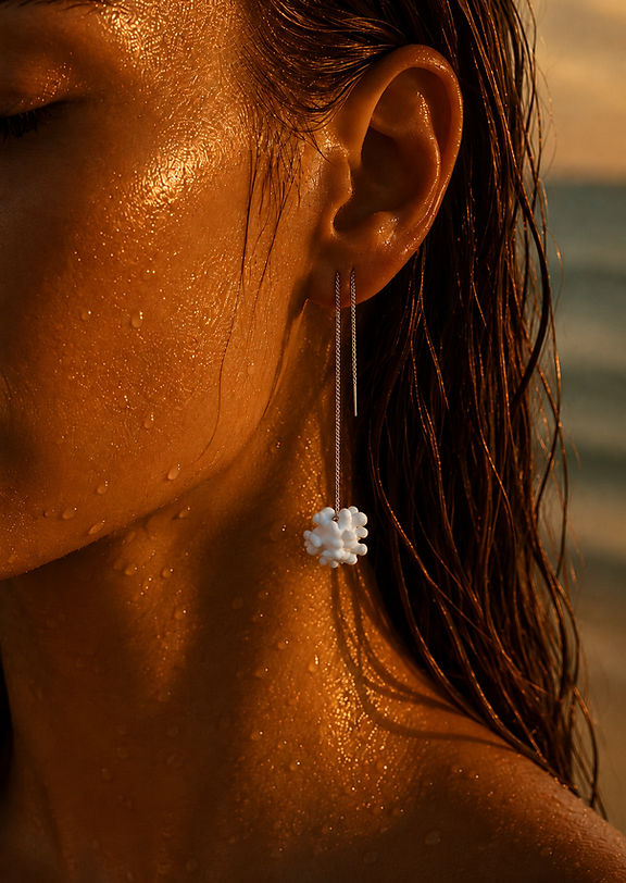Woman wearing white coral inspired drop earrings by Khoraia at sunset