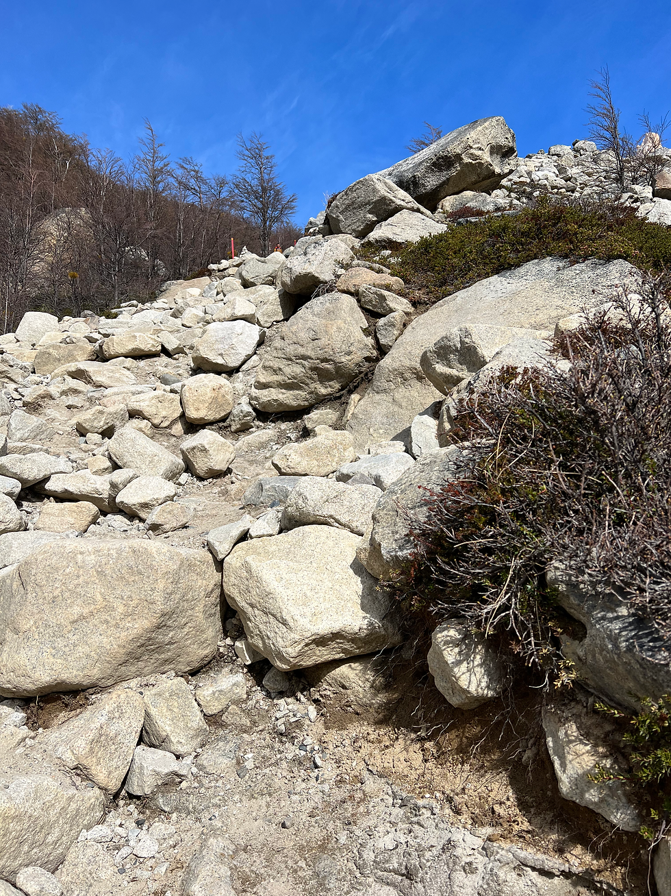 Steep rocky ascent with hikers climbing large boulders on the final mile of Mirador Las Torres trail.