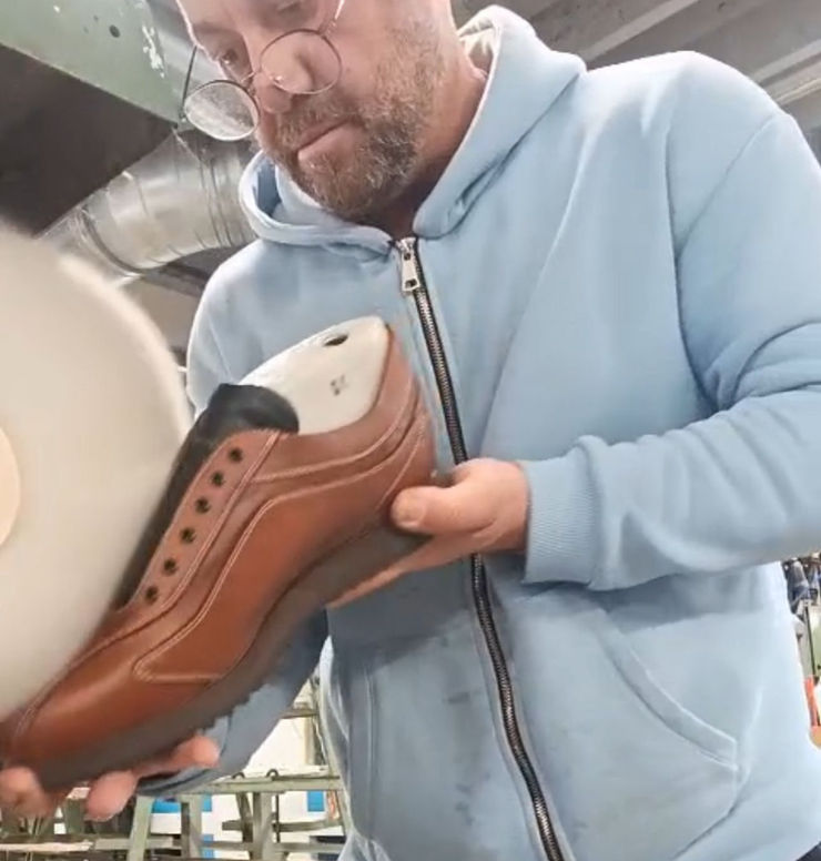 An artisan's hand meticulously carving a leather pattern inside a traditional Italian workshop.