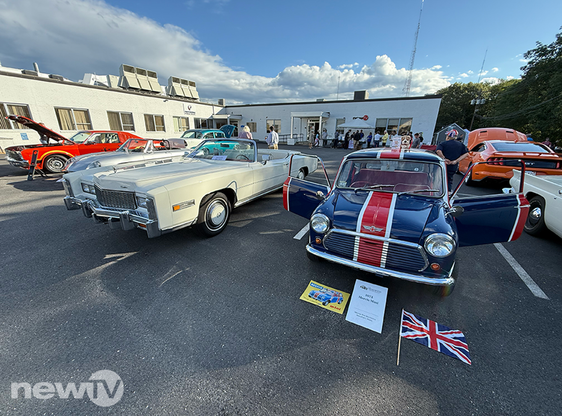 Several classic cars, including a 1973 Mini painted like a British flag, in a parking lot.