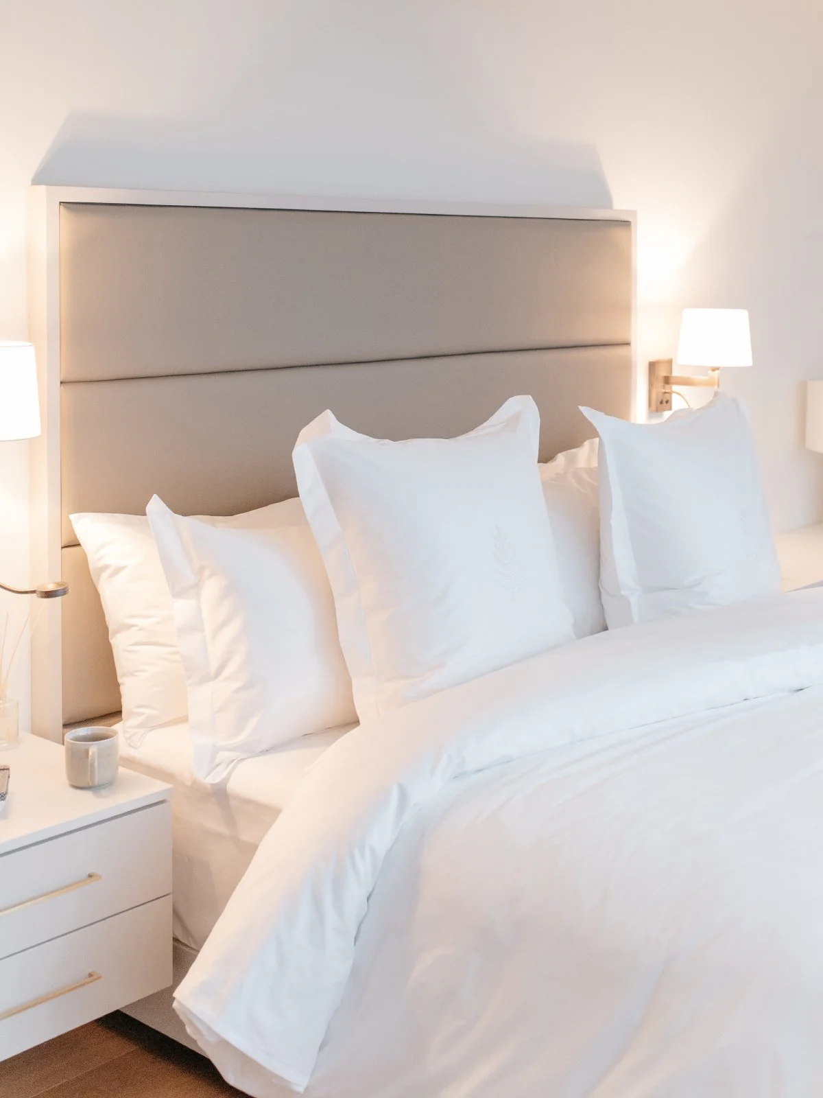 Luxury hotel bedroom inspired by Four Seasons with premium white bedding, elegant upholstered headboard, soft ambient lighting, and timeless five-star hotel style.