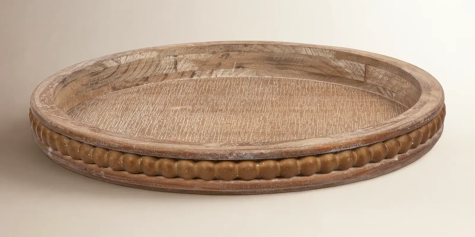 Oval carved wooden tray with a weathered brown finish on a plain beige background, shown alone with no text.