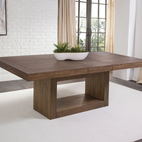 Modern extendable wood dining table with pedestal base for farmhouse, transitional, and quiet luxury dining rooms in warm neutral interiors.