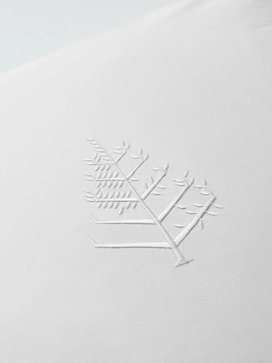 Close-up of the embroidered Four Seasons logo on premium white hotel linens crafted for a luxury hotel bedroom.