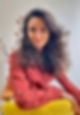Photo de profil de Camille Boré. Vêtement de couleur terracotta, assise sur une chaise jaune.