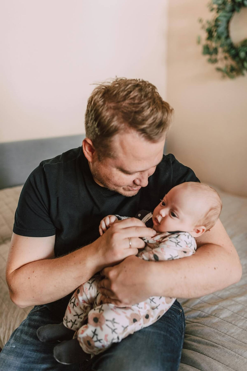 Father gently cradling infant on couch in tender moment - even during loving interactions like this, fathers with low self-esteem doubt their abilities, and a postpartum therapist in Des Plaines, IL helps dads build confidence in paternal bonding with newborn Des Plaines, IL. Des Plaines, IL | Glenview, IL | Northbrook, IL