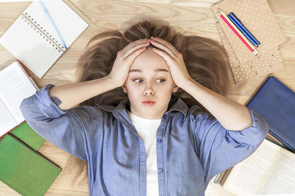 Image of a stressed teen girl laying on the floor surrounded by books | therapy for teens in manhattan, ny | teen therapist in manhattan, ny | exam stress | anxiety in teens | online therapy for teens | 10023 | 10028 | 10013