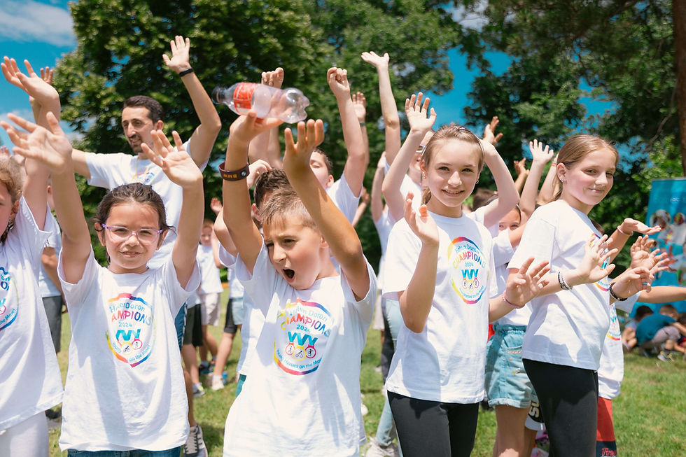 Kids in white shirts raise hands and smile at a sunny outdoor camp, with trees and blue sky behind | parent coaching in Boulder County, CO | parent coach | anxiety in kids | Boulder | Arapahoe | Foothills