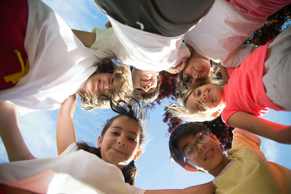 Six children form a huddle, smiling under a clear blue sky | parent coaching in Boulder County, CO | parent coach | parent coaching therapy | Boulder County | Boulder | Louisville