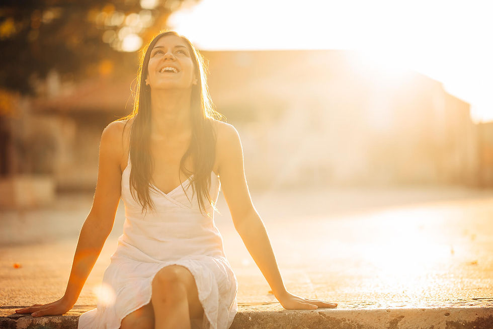 Image of a smiling woman sitting on a concrete wall as the sun shines on her | life transitions therapy in raleigh, nc | life transition therapist in raleigh, nc | life change counseling | online therapy | 27603 | 28557 | 28715