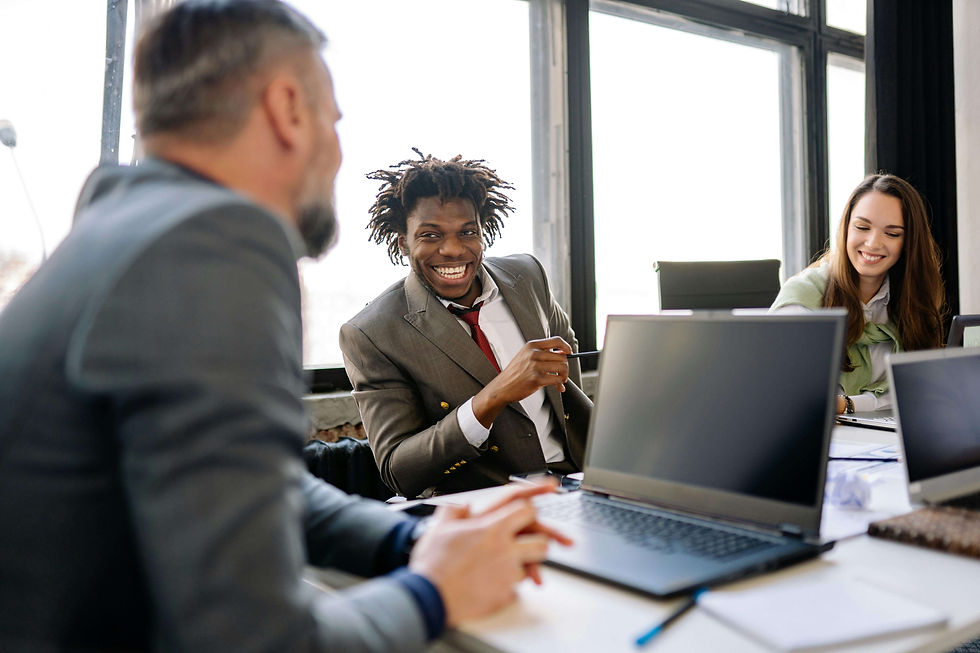 Three people engaging in a lively meeting at an office table with laptops | anxiety therapy in Manhattan, NY | anxiety therapy | anxiety therapy for professionals | Upper West Side | Upper East Side | Financial District
