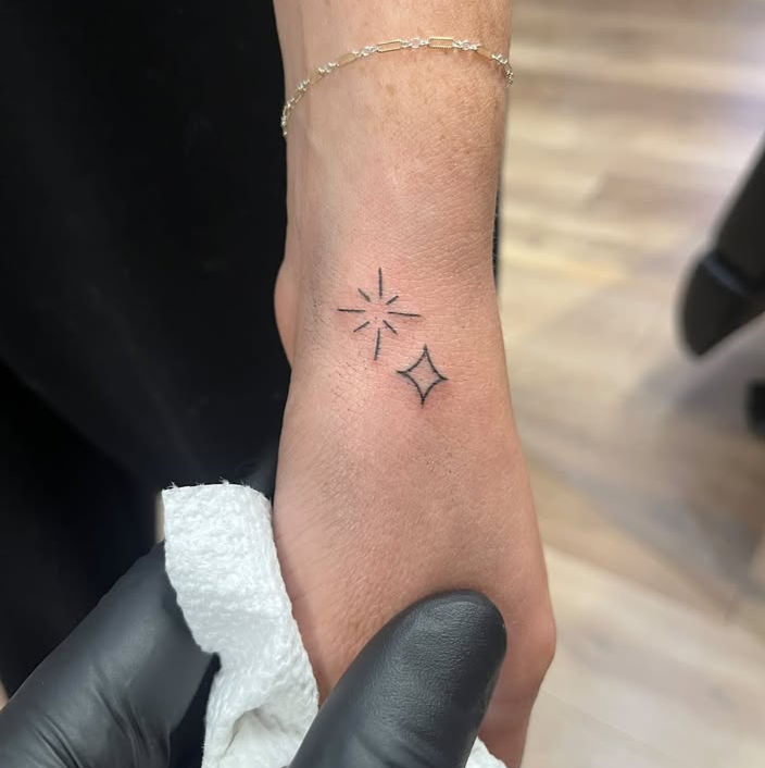 Small fine line star and sparkle tattoos on the hand and wrist, tattooed at Linden Street Tattoo Company in Fort Collins.