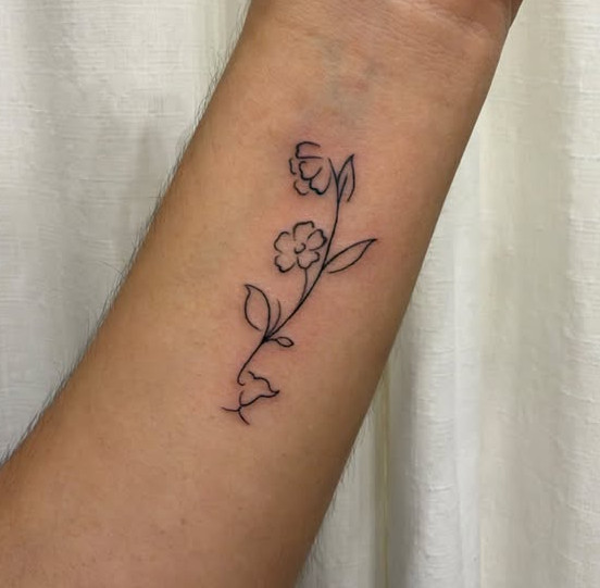 Fine line floral tattoo with a minimalist cat face worked into the stem, tattooed on the inner forearm at Linden Street Tattoo Company in Fort Collins, Colorado.