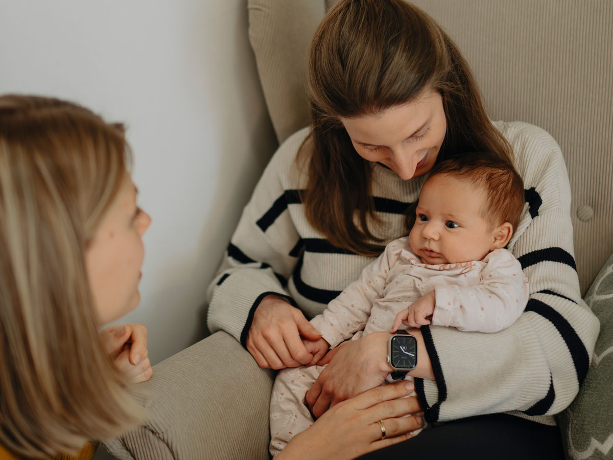 Lara im Gespräch mit einer Mutter, die ihr Baby hält