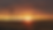 Wind turbines silhouetted against a brilliant sunset over a golden grain field.