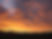 Golden and purple sunset clouds over mountain silhouettes.