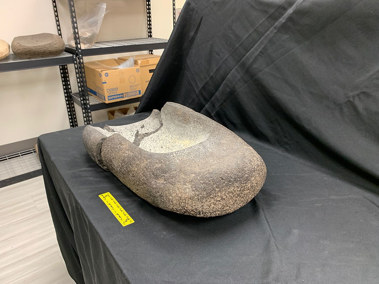 Ancient stone mortar on a black cloth-covered table.