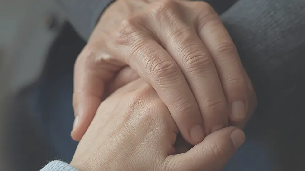 Close-up of two hands gently clasped in a comforting hold against a soft gray background