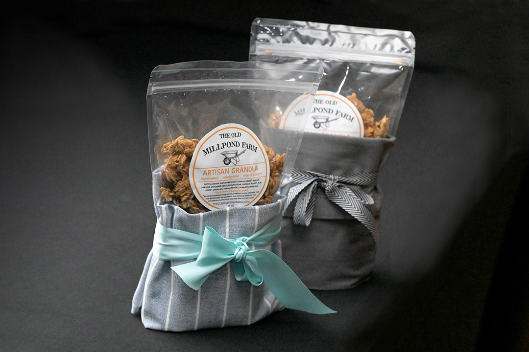 Two bags with The Old Millpond Farm Artisan Granola labels and blue and grey bows.