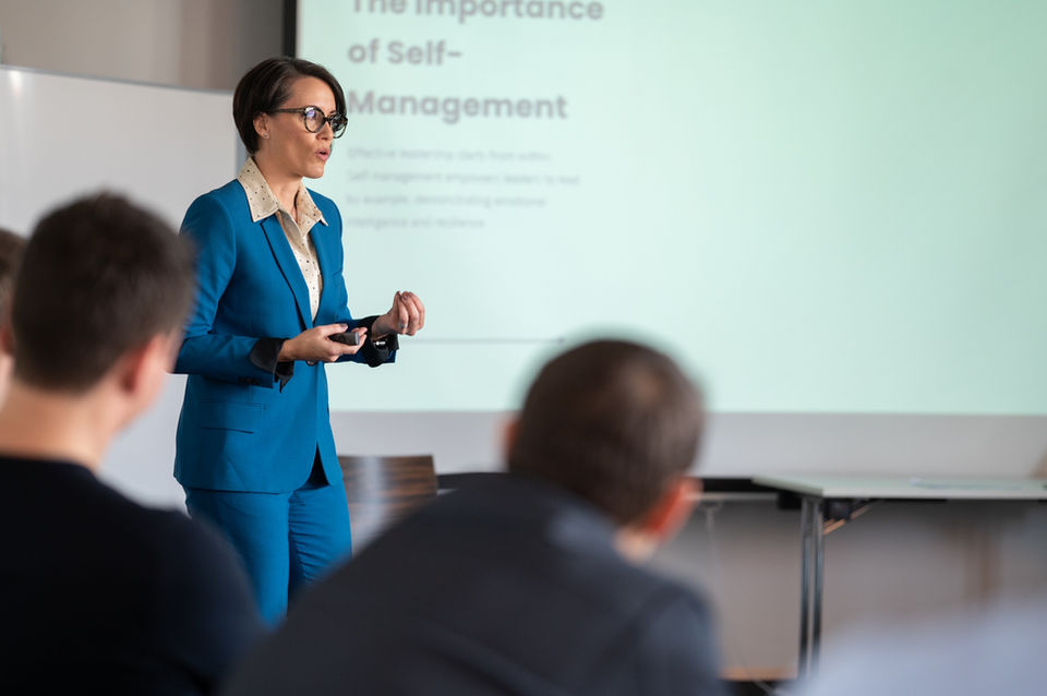 Action image of Liza in front of a screen, speaking to the audience