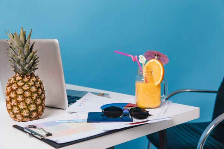 Modern bir ofis ortamında bilgisayar başında çalışan hamile bir kadın ve ayakta tablet üzerinden toplantı yapan insan kaynakları ekibi.