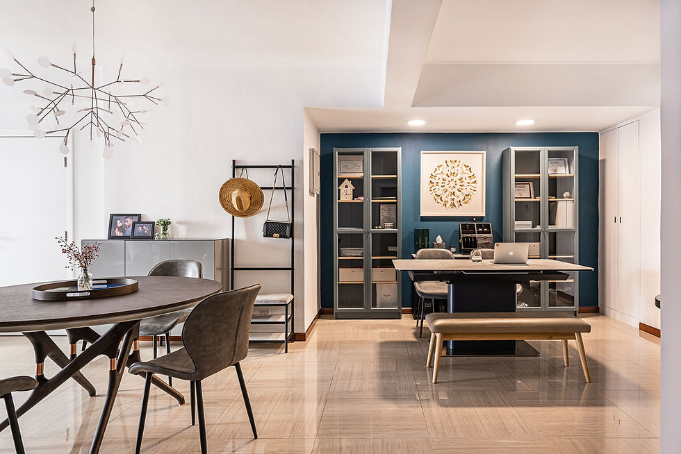 Modern dining and study area with dark table, grey chairs, and a blue wall with shelves. A laptop on the desk, decorative chandelier. Calm ambiance.