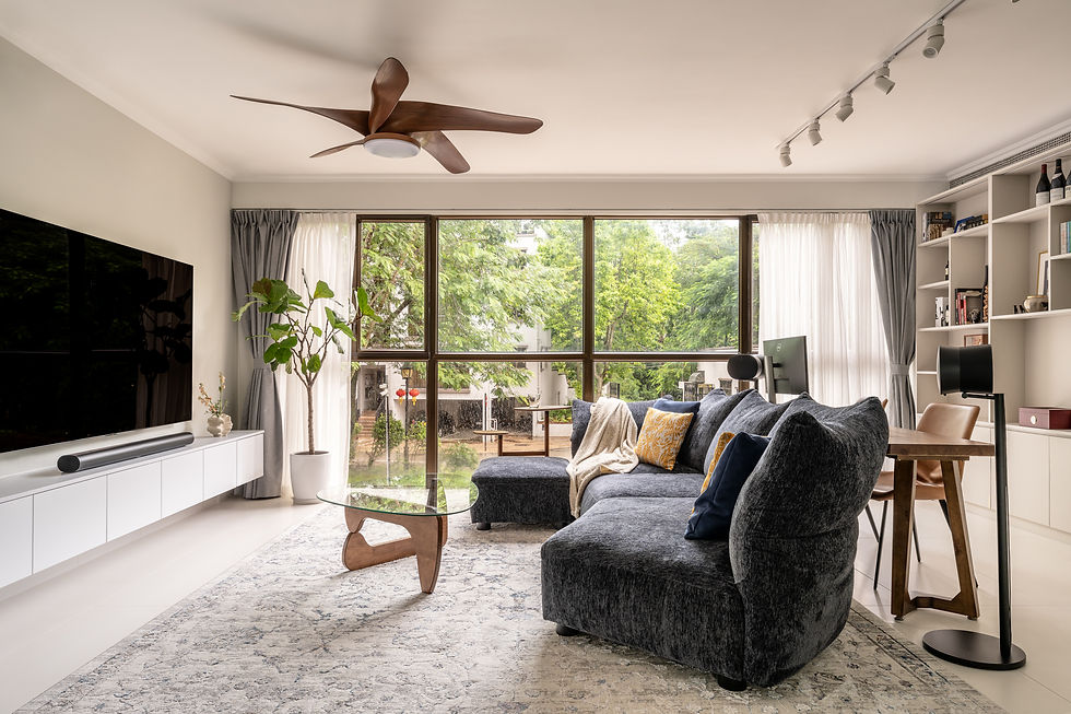 Modern living room with a gray sofa, wooden coffee table, and large windows overlooking greenery. Neutral tones and minimalist decor.