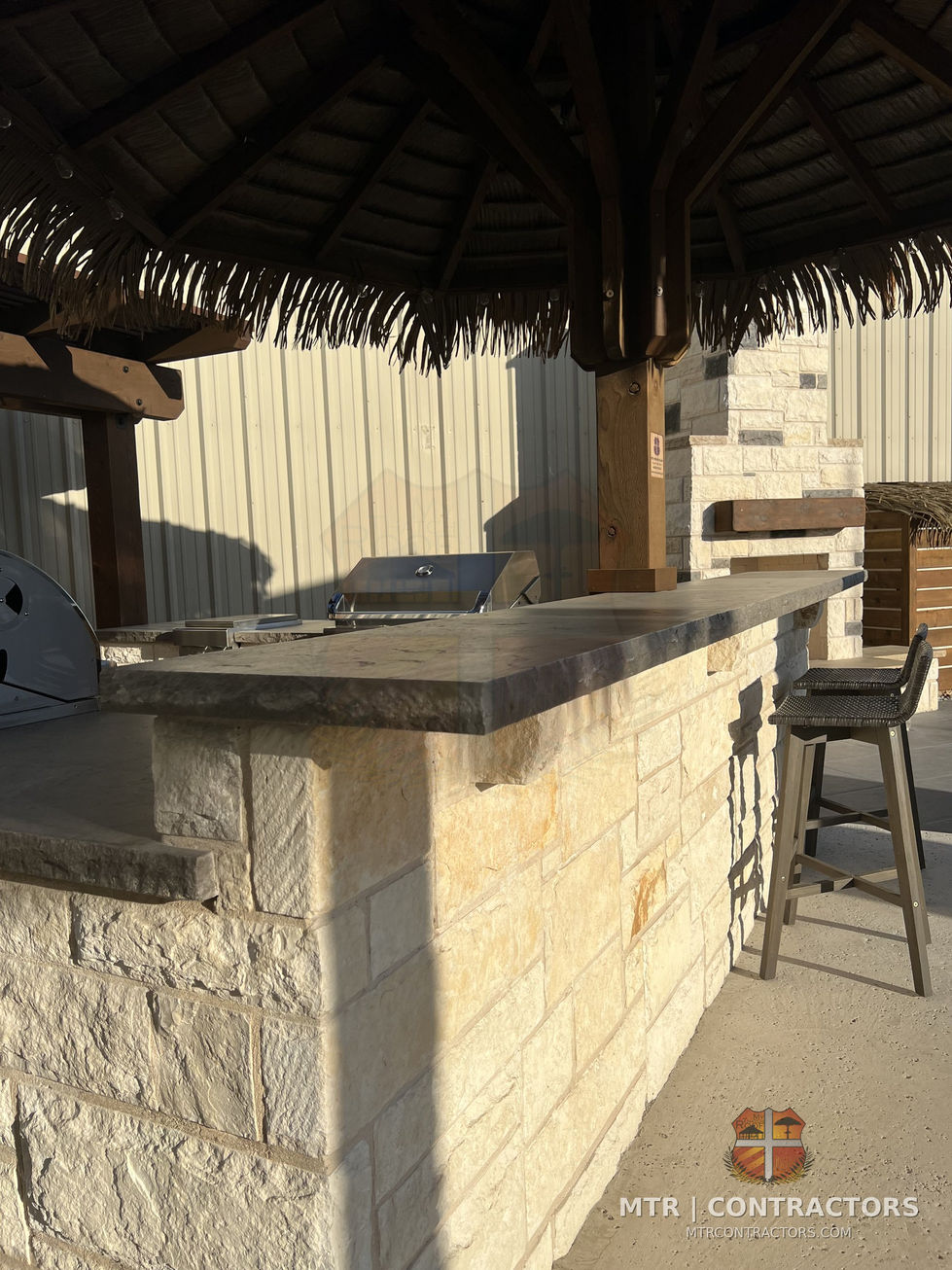 Masonry kitchen island under a shade structure in the showroom yard — outdoor living showroom in Frisco, TX