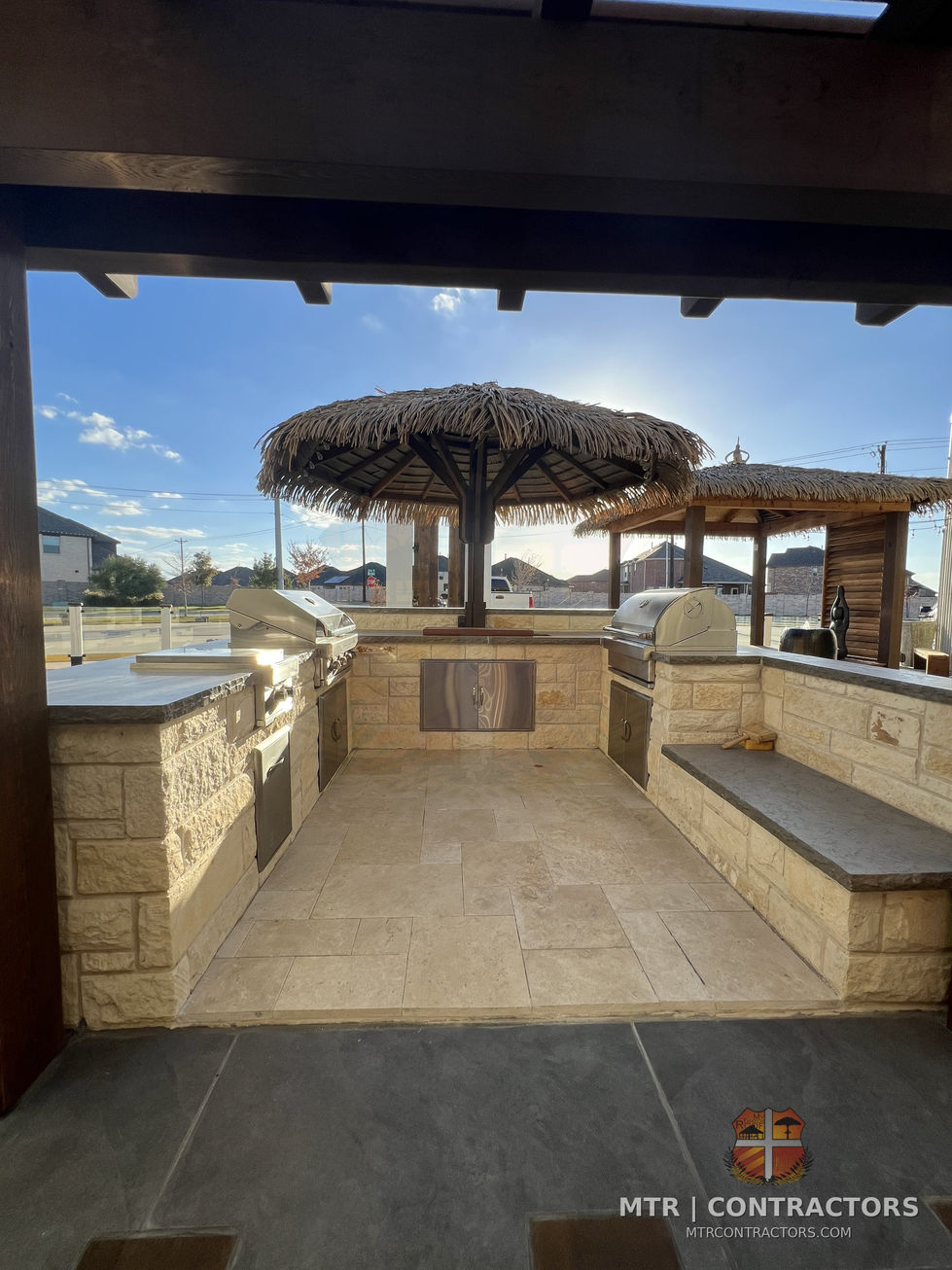 Outdoor kitchen and bar with counter seating and accent lighting — outdoor living showroom in Frisco, TX