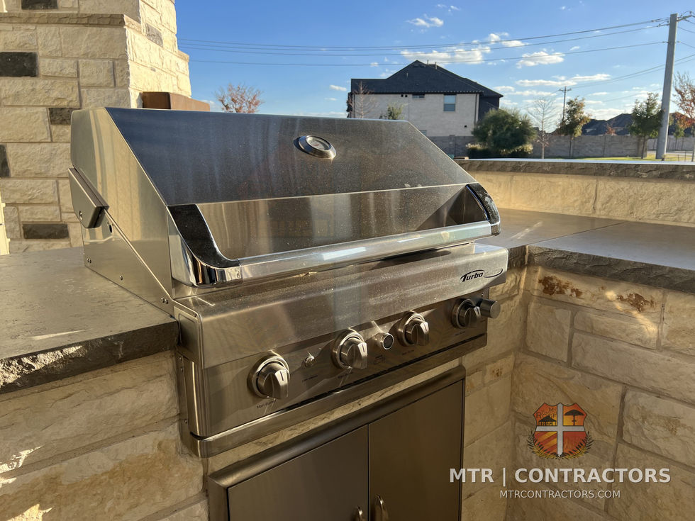 Stainless built-in gas grill set into a stone island with vented opening — outdoor living showroom in Frisco, TX
