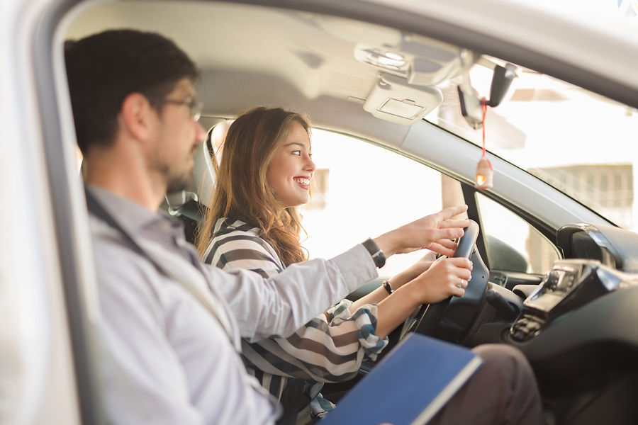 View of a male instructor giving instructions to a smiling female driver