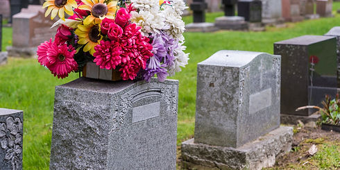 Flowers on a tombstone in a cemetery with headstones in the background