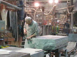 A stonemason in a workshop working on a gravestone