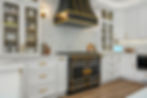 Close-up of luxury black and gold kitchen range with brass hardware and white cabinetry, photographed in Folsom, California b