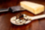 Das Bild zeigt eine Nahaufnahme eines hölzernen Löffels mit handgemachter Pasta, die mit Trüffel belegt ist. Im Hintergrund l