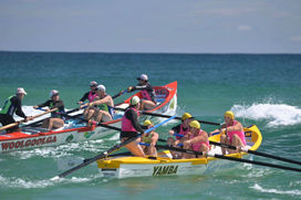 Two teams on surf boats in the waves at Yamba Main Beach.