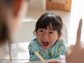 Angry child in floral blue shirt yelling at a parent, mid-meal — a visual example of emotional dysregulation in young children