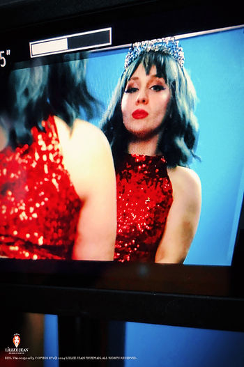 Lillee Jean on set The Trapper Trap. Woman in a red sequin and tiara looks into a mirror, reflecting a confident expression. Blue background adds contrast. Official Editorial Series: Lillee Jean Editorials of Twenty-Four. Directed by Lillee Jean. This image is part of a 560-photo group registration (VA0002501283). Subject is Actor/Director Lillee Jean Trueman. All rights reserved.