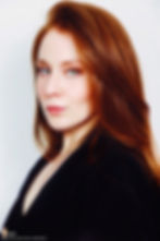 Lillee Jean Trueman official director and actress, in a professional portrait 2025. She is wearing a black blazer with her red hair side-parted, highlighting her fierce blue-green eyes.