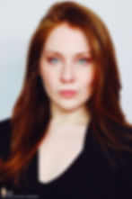 Lillee Jean Trueman official director and actress, in a professional portrait 2025. She is wearing a black blazer with her red hair side-parted, highlighting her fierce blue-green eyes.