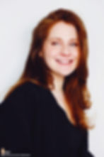 Lillee Jean Trueman official director and actress, in a professional portrait 2025. She is wearing a black blazer with her red hair side-parted, highlighting her fierce blue-green eyes.