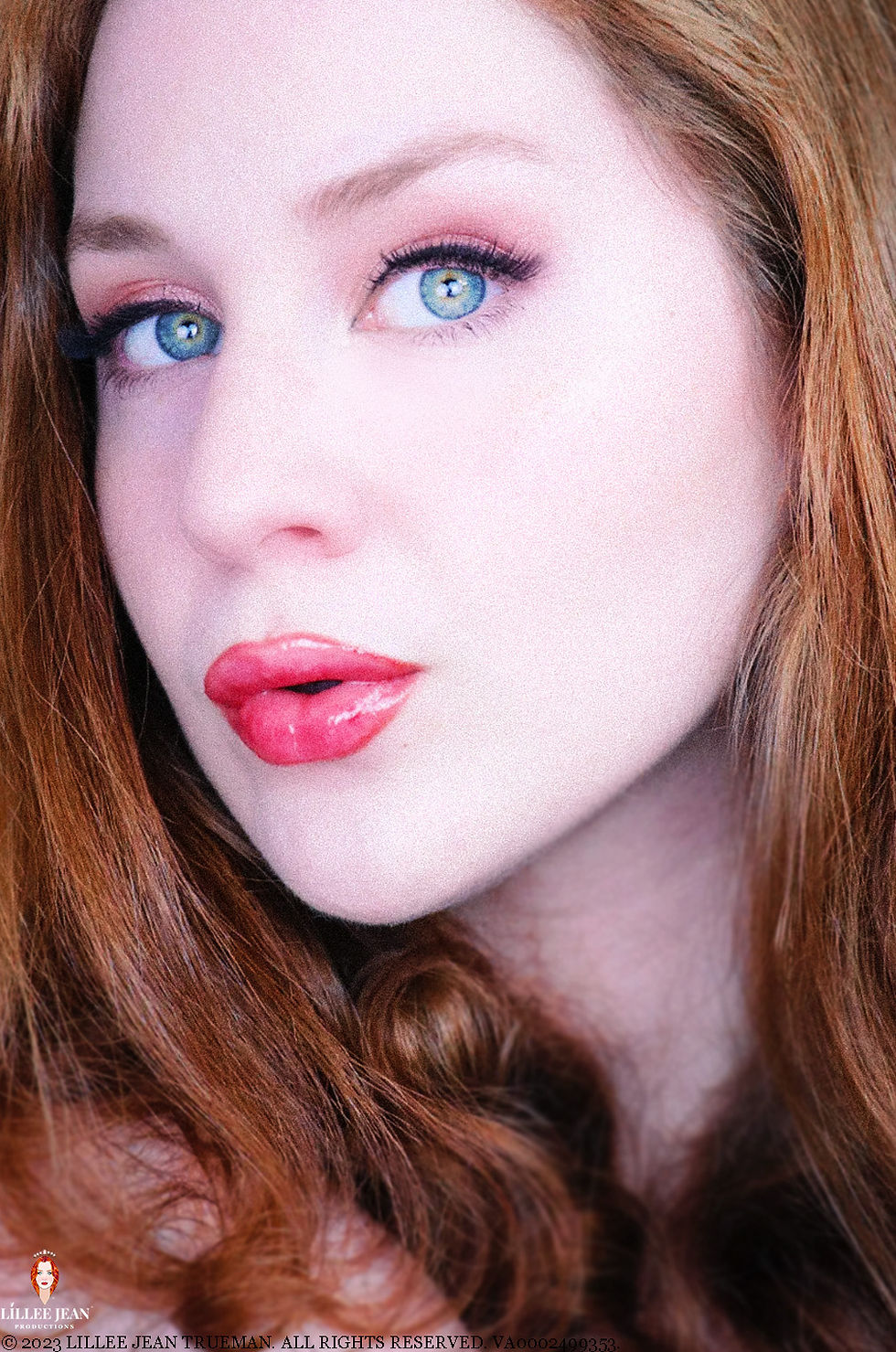 Close-up portrait of a red-haired woman with blue eyes and glossy lips; Lillee Jean watermark at bottom.