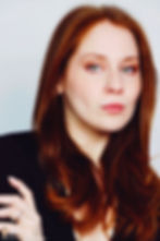 Lillee Jean Trueman official director and actress, in a professional portrait 2025. She is wearing a black blazer with her red hair side-parted, highlighting her fierce blue-green eyes.