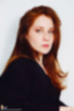 Lillee Jean Trueman official director and actress, in a professional portrait 2025. She is wearing a black blazer with her red hair side-parted, highlighting her fierce blue-green eyes.