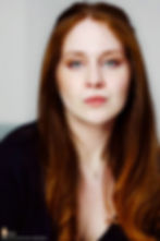 Official portrait of actress Lillee Jean Trueman wearing a navy blue T-shirt and a pearl heart necklace, with her red hair styled half up 2025.