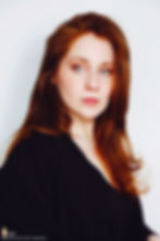 Lillee Jean Trueman official director and actress, in a professional portrait 2025. She is wearing a black blazer with her red hair side-parted, highlighting her fierce blue-green eyes.
