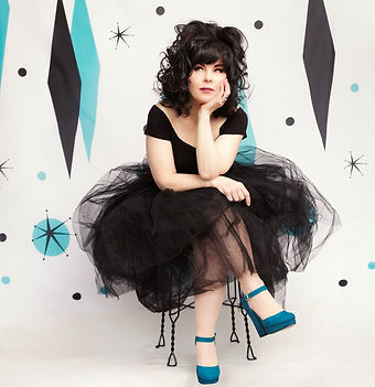 Lulu, the Calgary Brazilian wax specialist sitting in a chair legs crossed, chin on palm, thinking