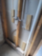 Plumbing pipes behind wall studs during professional renovation services.